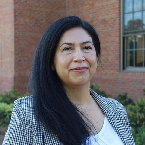 A woman wearing formal attire and having long dark hair is outside.