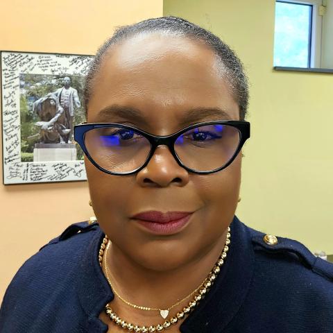 A woman wearing dark framed glasses slightly smiles