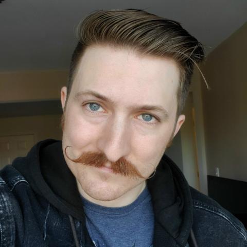 A man with a mustache smiles.