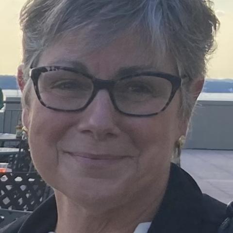 Profile of a woman wearing glasses, smiling.