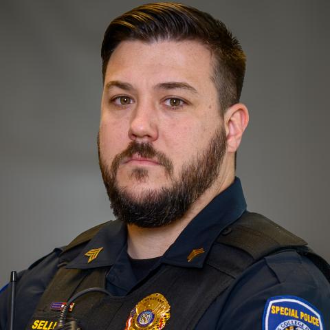 A police officer in uniform with a badge, radio, and “Special Police” patch stands facing forward against a neutral background.