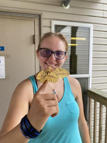 Marzec standing outside holding a moth 