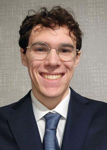 Professionally Dressed Man Behind a white background with small designs in it.