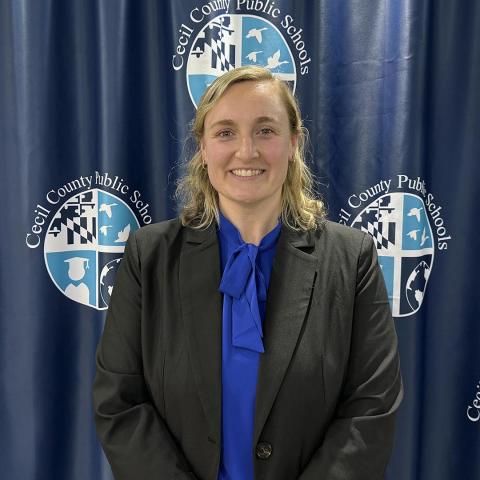 A woman with blonde hair in a suit indoors in front of a Cecil County Public Schools backdrop.