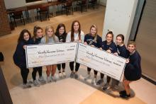 Varsity Women's Lacrosse team holding winning checks