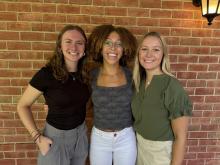 An image of Shelby Ditman, Britney Douglas and Sara Dapp outside infant of a brick wall 