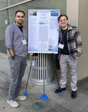 Anish Agashe (left) and Alex Stornelli (right) stand on either side of a conference poster displayed on a stand outdoors, both smiling at the camera.