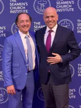 Two men in suits pose and smile in front of a step-and-repeat backdrop with "The Seamen's Church Institute" logo and text.