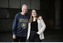An older man in an Apollo 13 sweatshirt and a young woman in a blazer stand side-by-side, smiling for a photo.