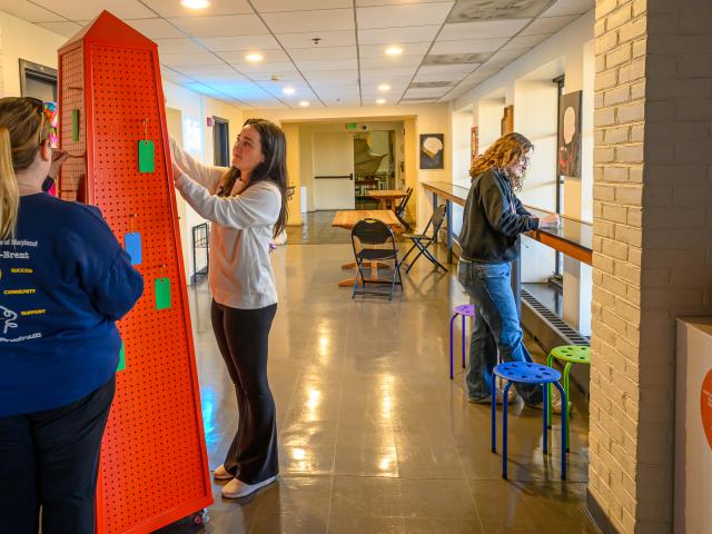 Two students place cards on Reflection Obelisk while third student fills out a card