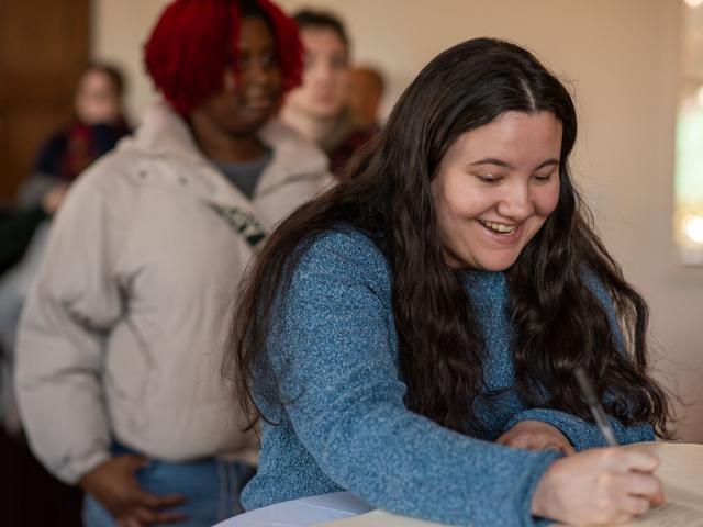 Student signing the President's Book with line of students behind her.