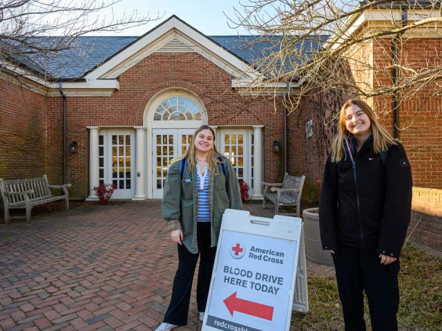 Two students standing next to blood drive sign outside Daugherty-Paler Commons