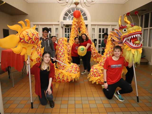 Students hold up decorative dragon In DPC 