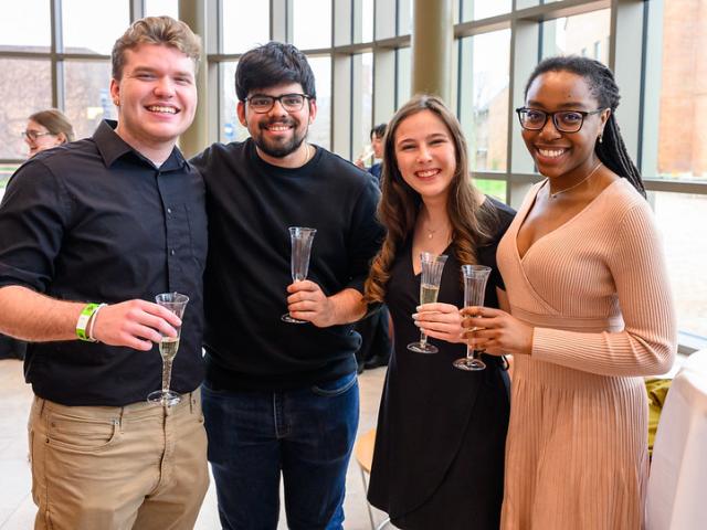 4 students holding champagne glasses