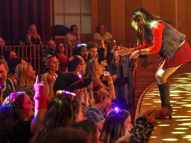 Singer on stage leans in toward crowd dancing in front of stage