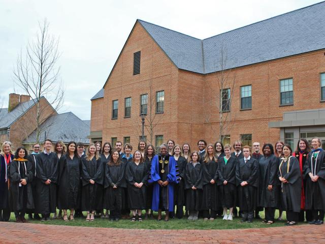 Group of students in faculty standing outside in academic robes