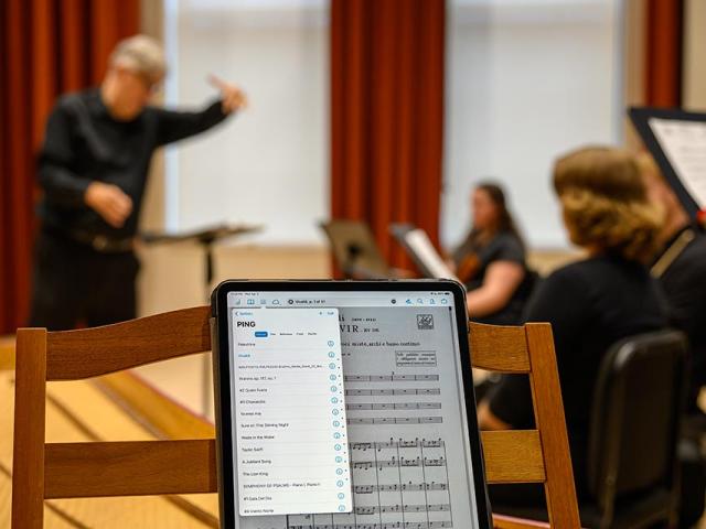Man conducting musicians and singers with harpsichord in foreground