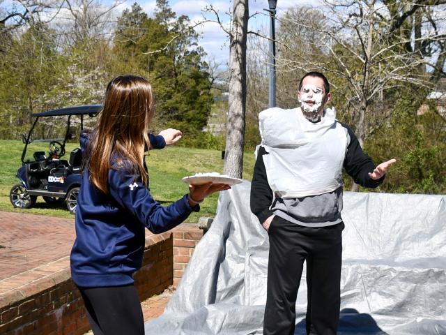 An athlete pies a coach at the campus center patio 
