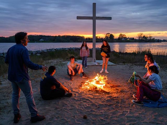 Photographer with students gathered around fire