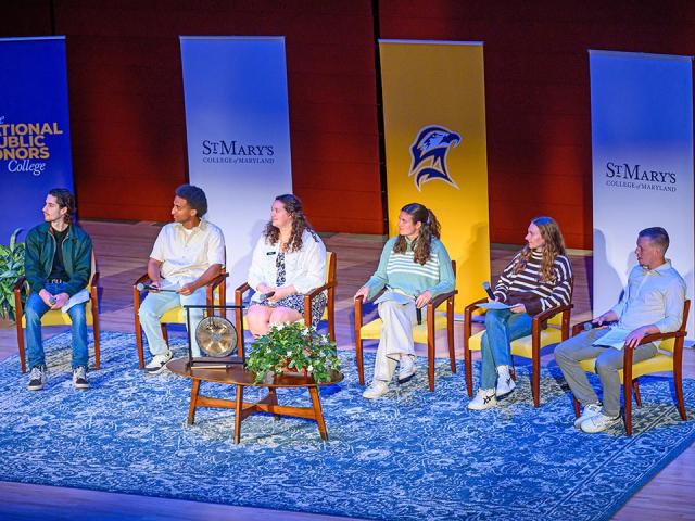 Six students seated on stage