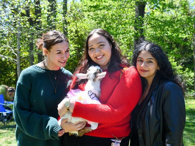 3 women one cuddling a baby goat