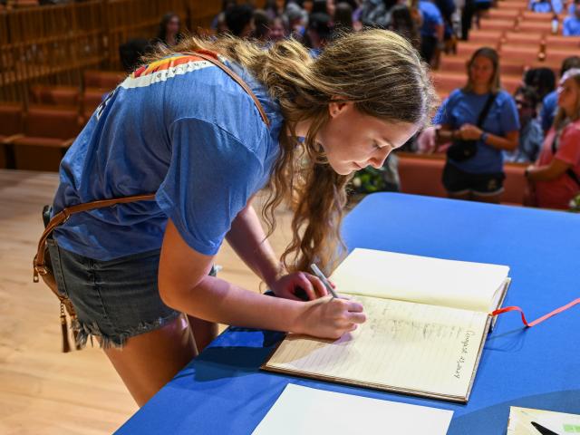 woman signs a book on stage 