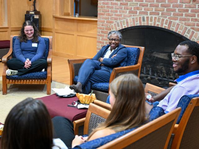 A group of people sitting in chairs having a conversation 