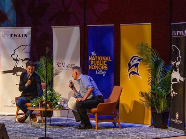 Two men seated on stage talking