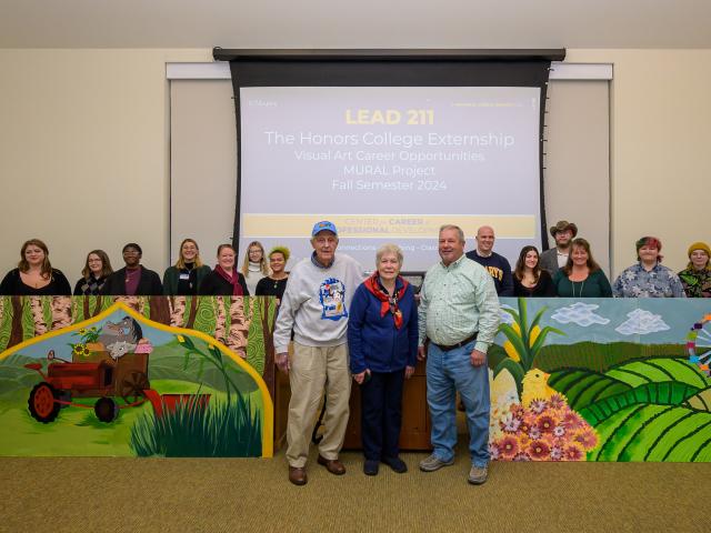 Students, staff and community members surround murals