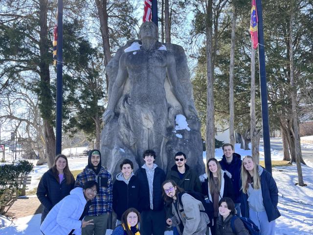 A group of people pose in front of a statue 
