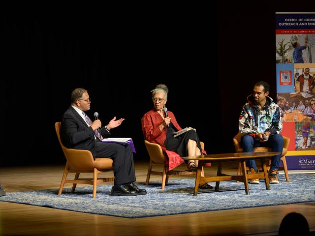 Three people sit on stage in chairs having a panel discussion, with Maryland Humanities and outreach banners in the background.