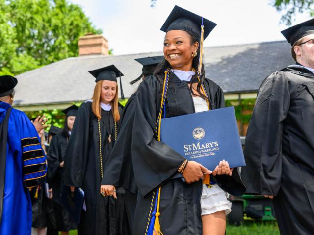 Graduates in cap & gown carrying diplomas