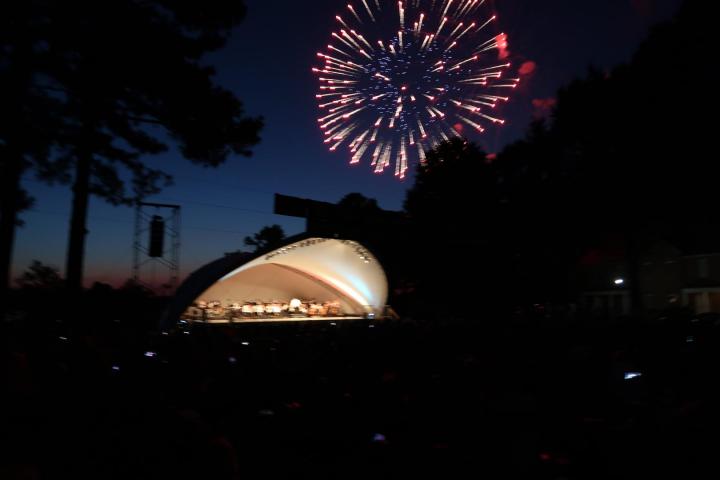 Firework bursts over the orchestra tent lit in the night sky on the St. Mary's River