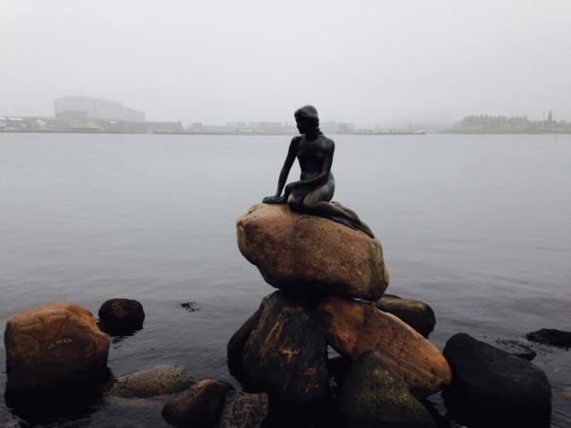 The Little Mermaid statue sits on a rock by the water's edge in Denmark, Copenhagen.