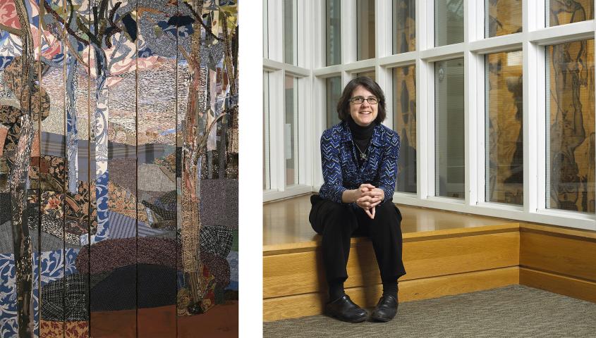 A woman with glasses, short dark hair, and a blue patterned shirt sits on a wooden bench by large windows. An abstract textile artwork is displayed on the left.