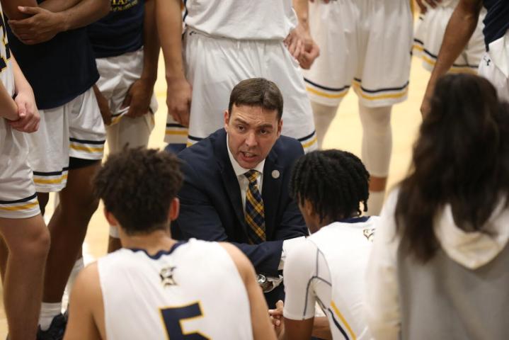 Chris Harney talking to players at halftime of men's basketball game 