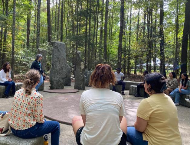 Students sitting around an outdoor sculpture at Annmarie Garden