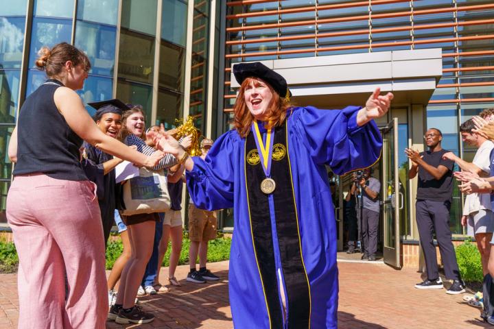 President Rhonda Phillips celebrates outside a building while a group of people clap and cheer.