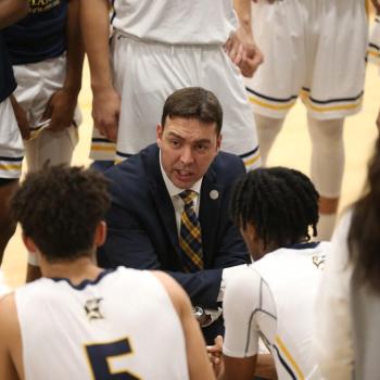 Chris Harney talking to players at halftime of men's basketball game 