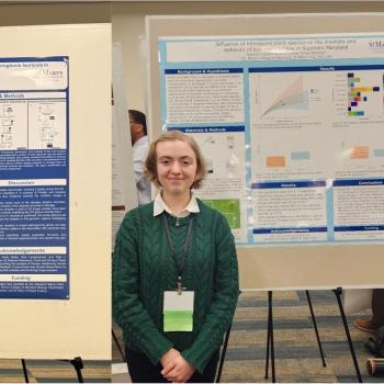 Three individuals stand next to separate research posters at a conference, each presenting scientific information with charts and text on display boards.