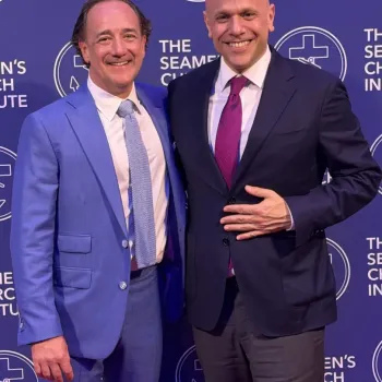 Two men in suits pose and smile in front of a step-and-repeat backdrop with "The Seamen's Church Institute" logo and text.